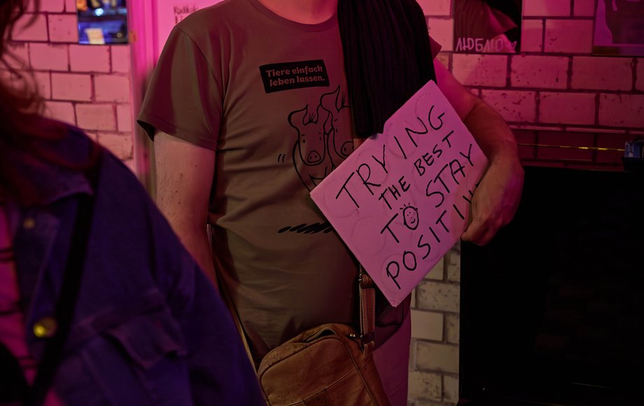 Ein Besucher hält ein selbst gemachtes Pappschild hoch mit der Aufschrift "Trying my best to stay positive".