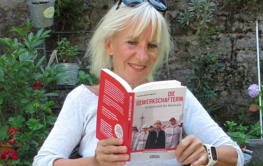 Frau sitzt in einem Gartenstuhl mit einem Buch in der Hand