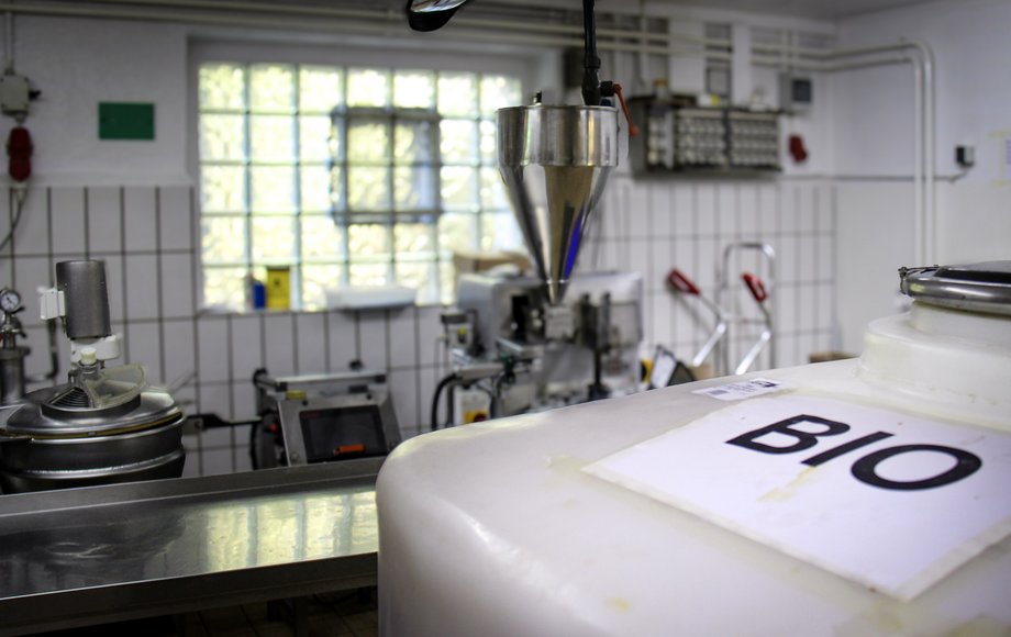 Manufaktur der Feinkostfirma Steck: Im Vordergrund ein weißer Behälter mit der Aufschrift «BIO», im Hintergrund Abfüllmaschinen und Verarbeitungsgeräte aus Edelstahl.