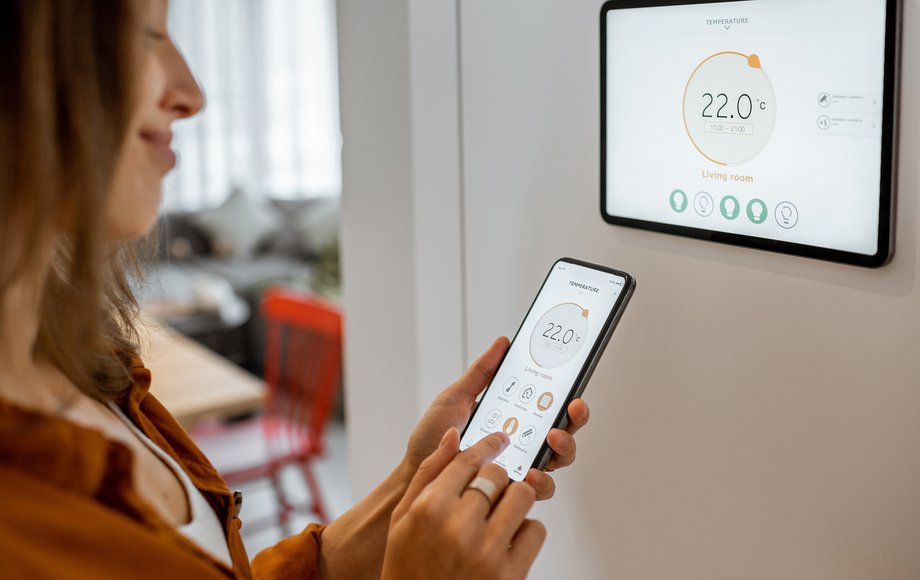 Frau regelt mit dem Smartphone die Raumtemperatur