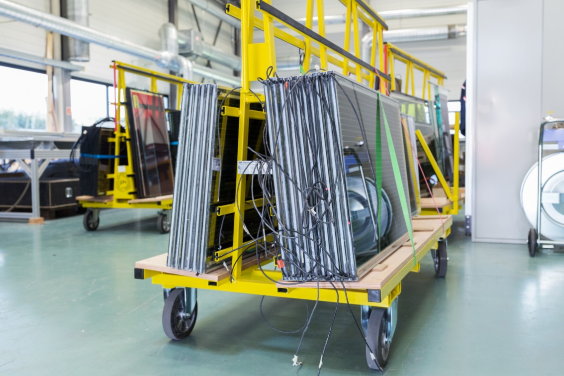 Die fertigen Energieglasmodule, die auf einem Lastenwagen in der Werkshalle lagern, sind mit Anschlusskabeln versehen.