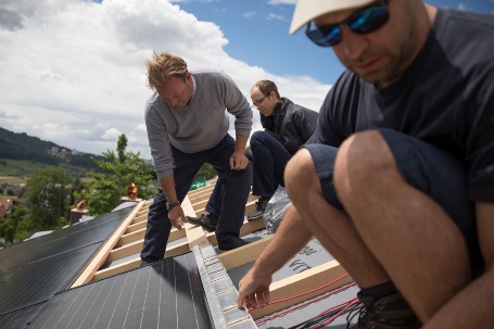 Auf dem Dach arbeiten die drei Männer zusammen an der Installation der Solaranlage.