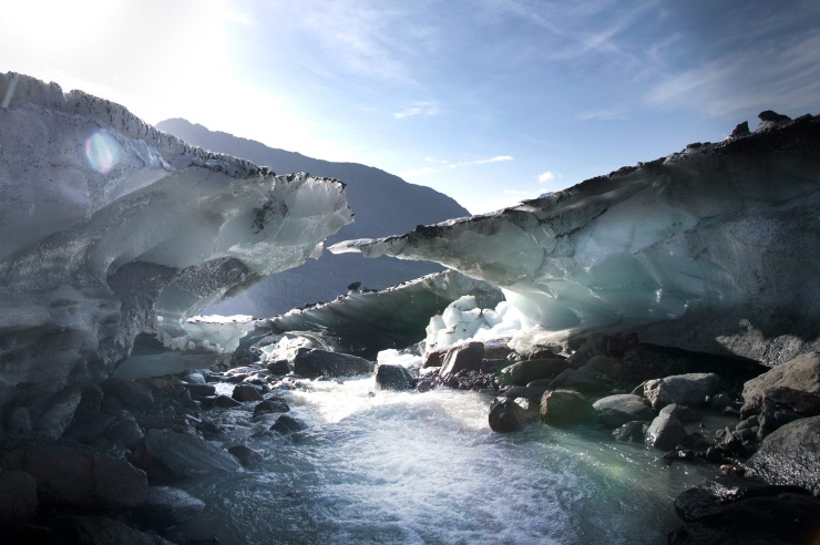 Aus schmelzenden Gletscherresten entspringt ein schnell strömender Bach.