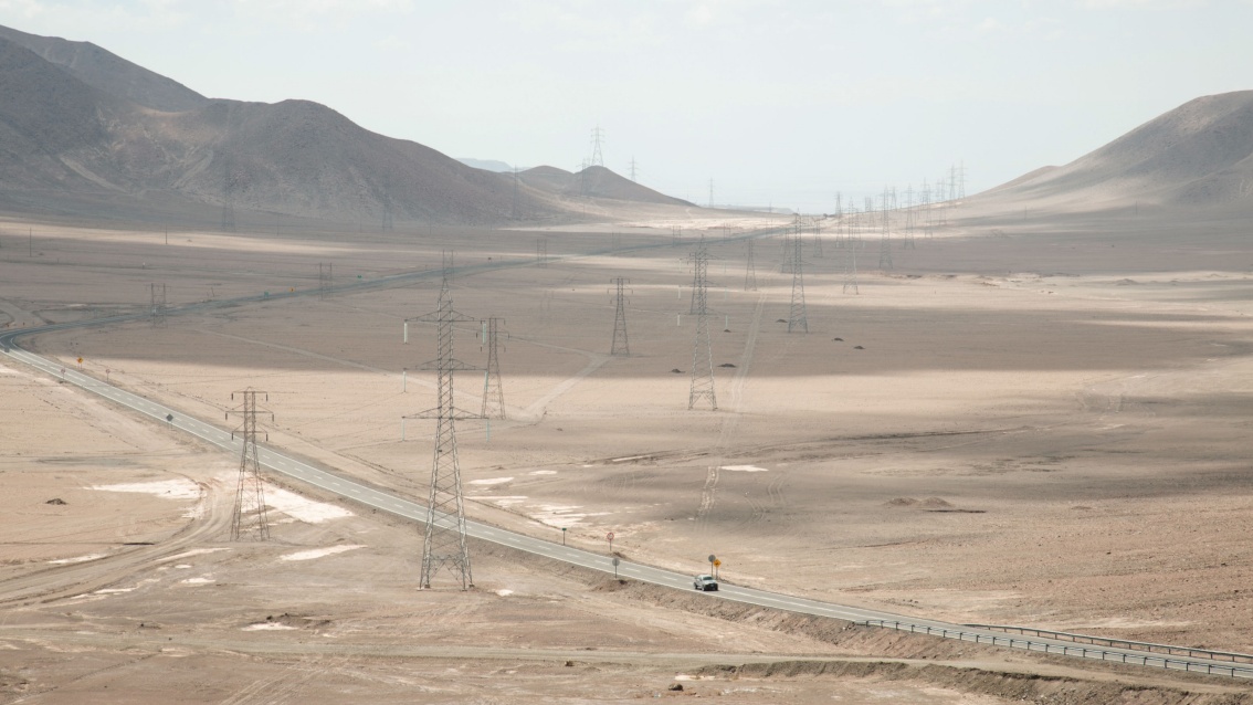 Eine Hochspannungs-Stromtrasse in einem weiten Wüstental