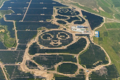 Luftbild eines riesigen Solarparks: Die hellen Wege zwischen den dunklen PV-Modulen bilden die Umrisse zweier Pandas ab..
