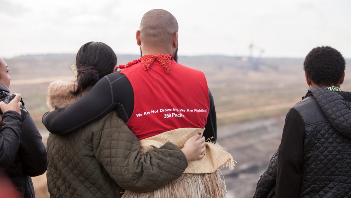 Joseph-Zane Sikulu und Kathy Jetnil-Kijiner halten sich im Arm und schauen auf das Tagebaugelände.