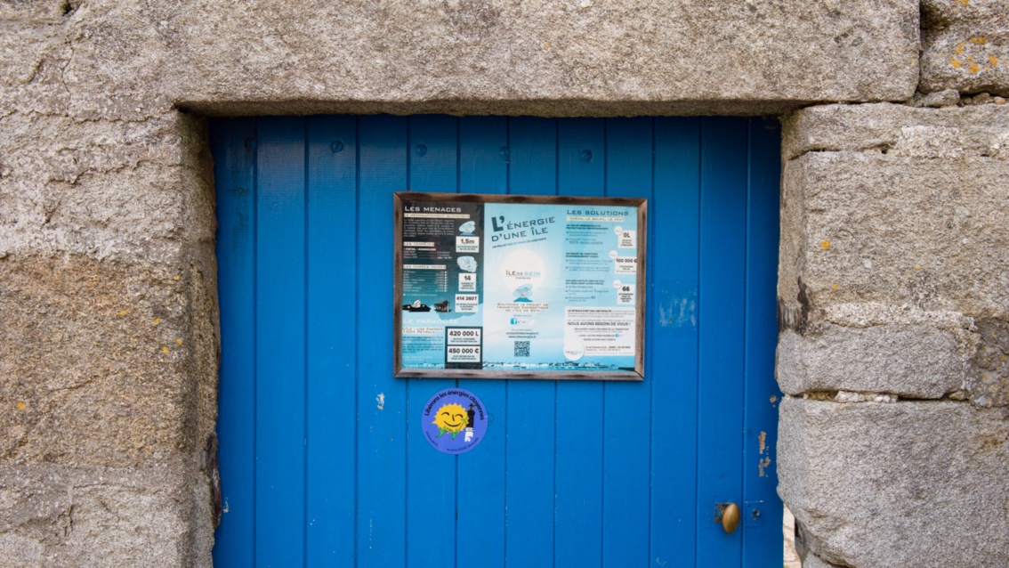 Eine alte blaue Holztür in einer steinernen Mauer trägt das Schild der IDSE.