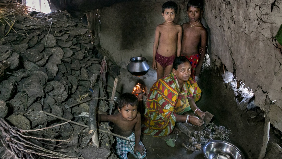Eine Großmutter mit ihren Enkeln posiert an ihrer Kochstelle.