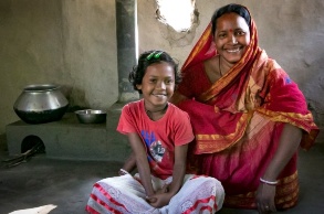 Indische Frau mit Tochter in einer Hütte vor neuem Herd