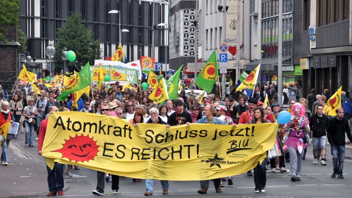 Großer Demozug in der Innenstadt, angeführt von einem gelben Banner auf dem steht: "Atomkraft Schluss jetzt! Es reicht!"