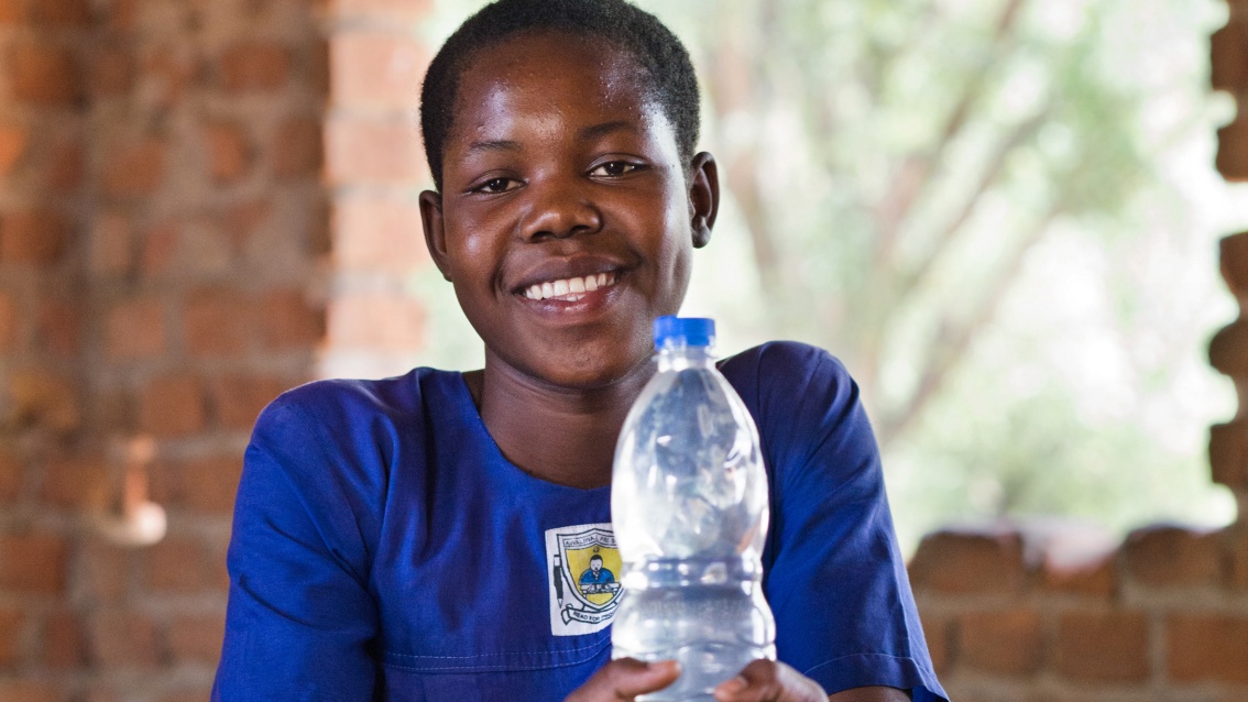 Porträt von Anuta mit einer Flasche Trinkwasser.