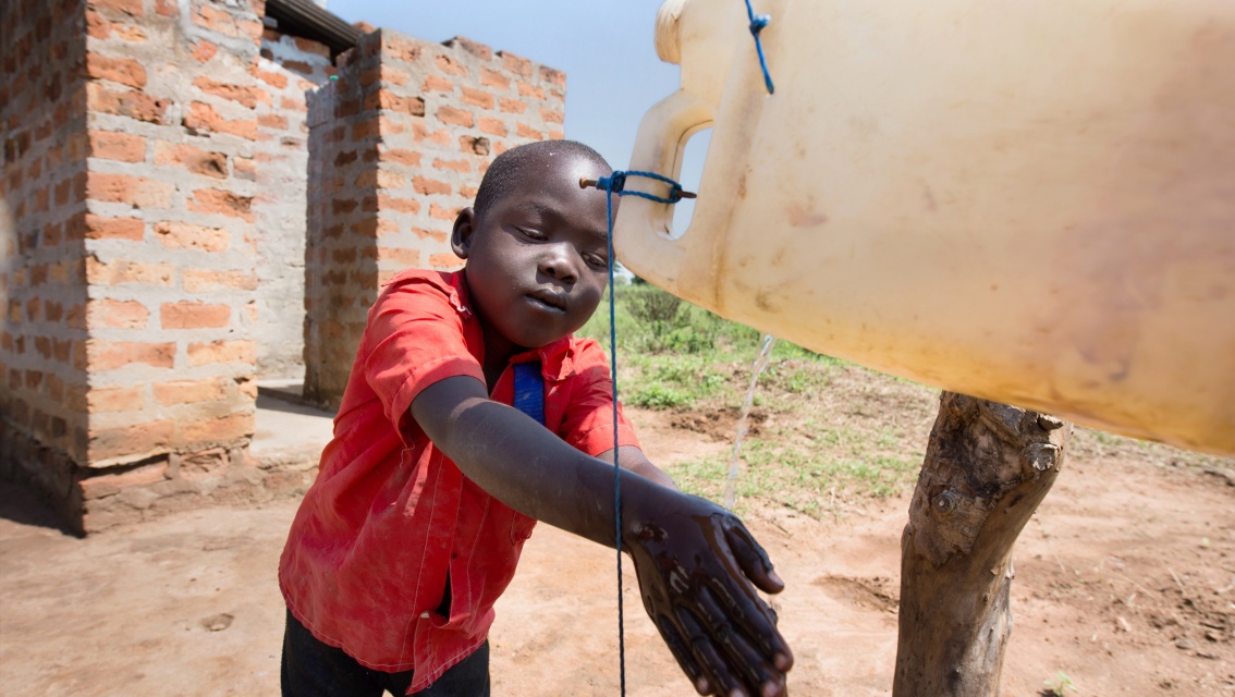 Ein Junge wäscht sich die Hände an einem Wasserkanister.