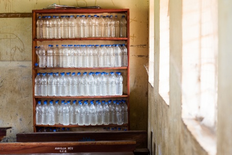 Ein Regal m Schulraum ist gefüllt mit Plastikflaschen voller Wasser.