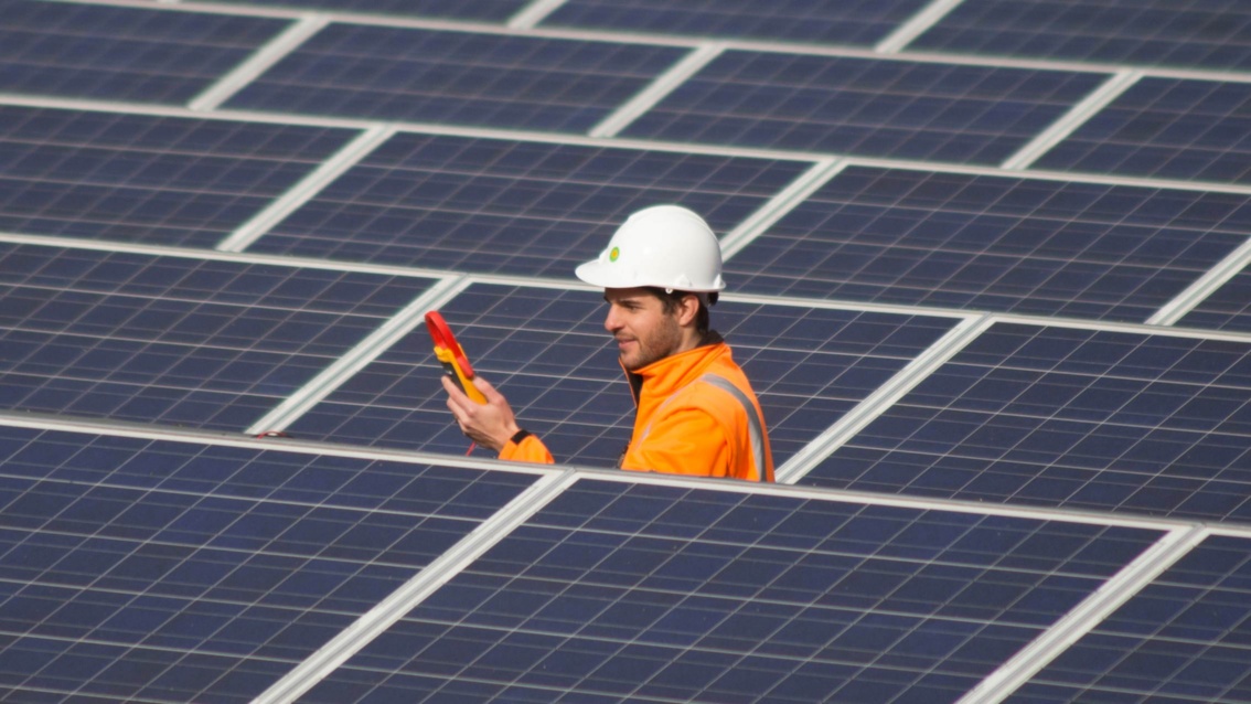 Ein Mitarbeiter der EWS mit Prüfgerät inmitten von Photovoltaik-Modulen
