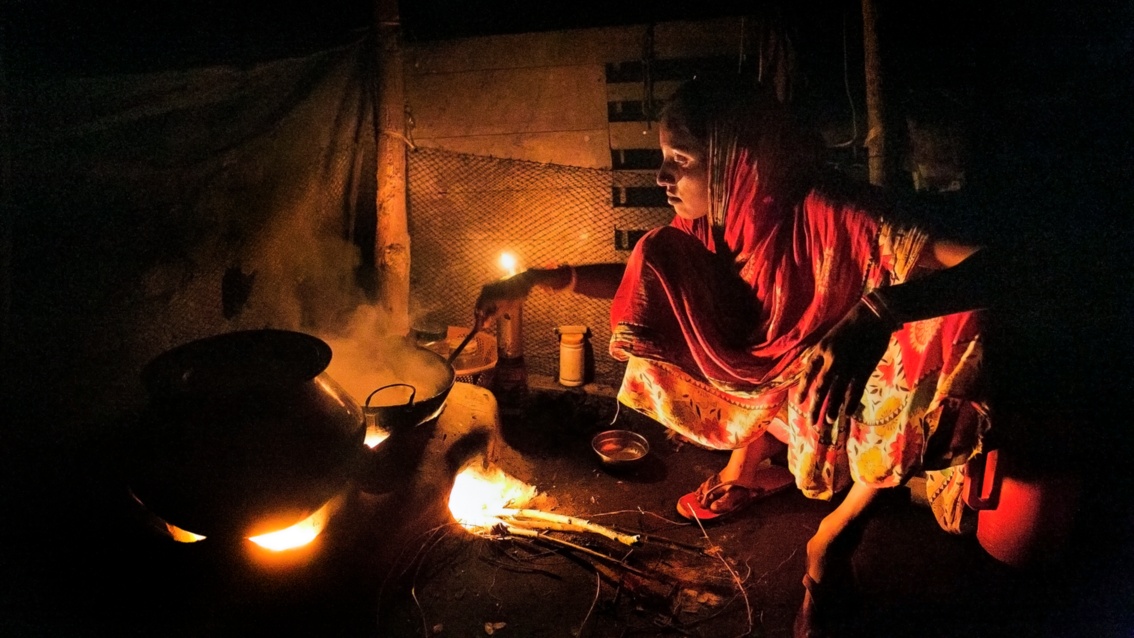 Eine indische Familie kocht in einem Haus an einer offenen Feuerstelle