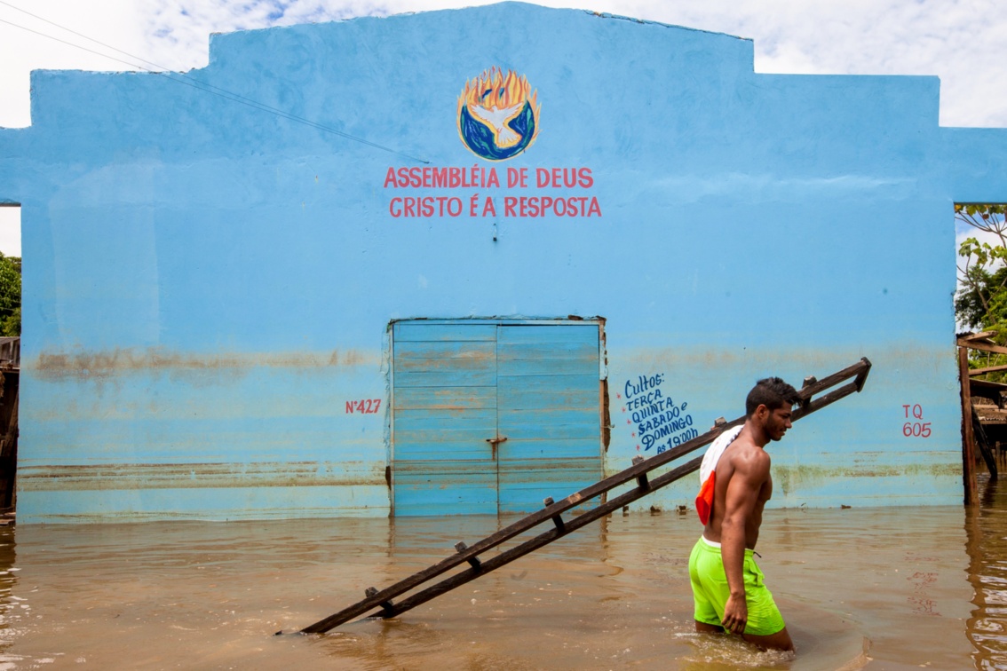 Ein junger Mann vor einem Kirchengebäude mit der Aufschrift "Assembleia de Deus – Cristo É eine Resposta", "Gemeinde Gottes – Christus ist die Antwort“.