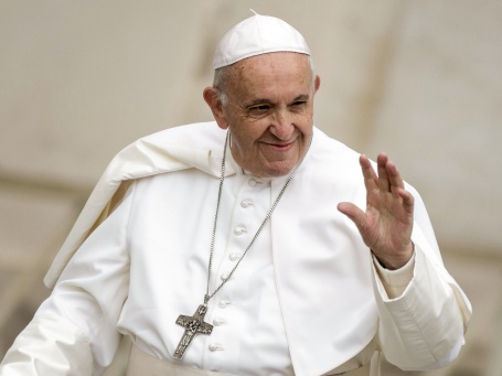 Papst Franziskus im weißen Gewand winkt freundlich.
