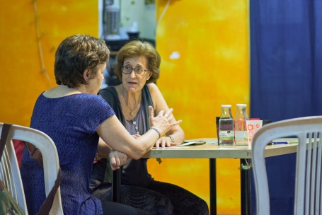 Zwei ältere Damen besprechen sich an einem Tisch.