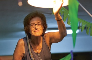 Eine ältere katalonische Genossenschaftlerin hält ihre linke Hand in des Licht einer Deckenlampe.