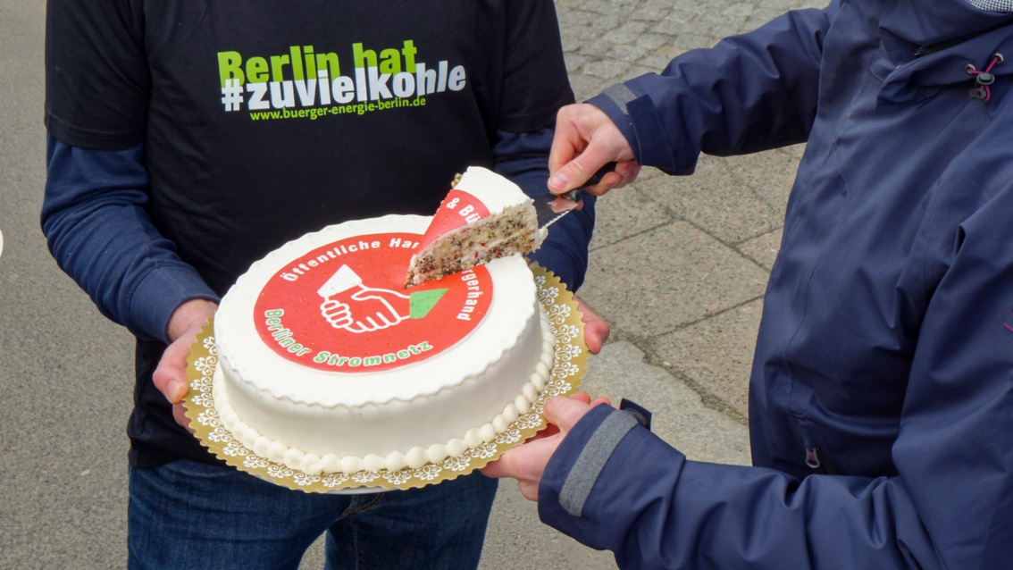 Die Torte wird angeschnitten. Auf der Torte die Aufschrift: «Öffentliche Hand und Bürgerhand – Berliner Stromnetz»