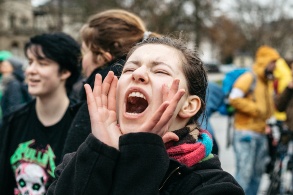 Ein Mädchen hält beide Hände trichterförmig um den Mund und schreit.