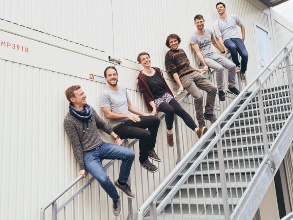 Ein Gruppe junger Menschen sitzt auf dem Geländer einer Metalltrappe