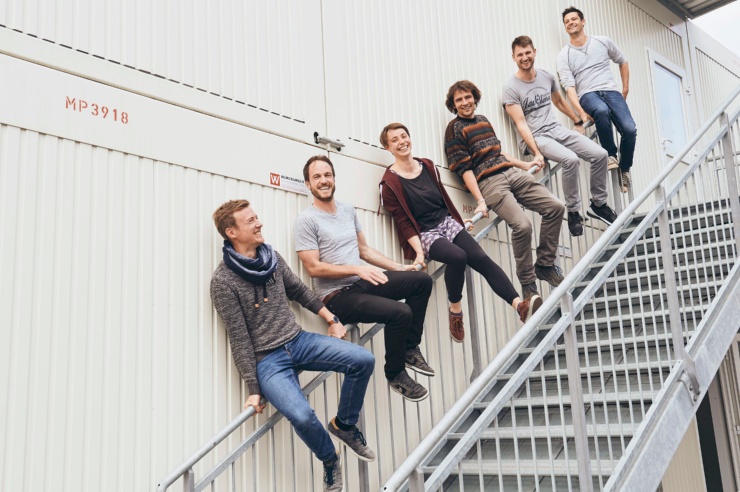 Gründer und Gründerinnen sitzen gemeinsam mit EWS-Mitarbeitern auf einem Treppengeländer.