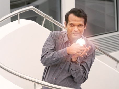 Mann auf einer Treppe, hält einen Spiegel mit Lichtreflexen in der Hand.
