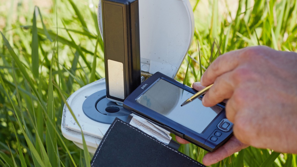Mit einem kleinen Handheld-Computer werden Notizen an einer Wasserstandsmessstelle gemacht.