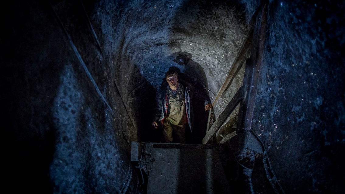 Ein Mann kommt aus einem vereisten Tunnel  eine steile Treppe herauf.