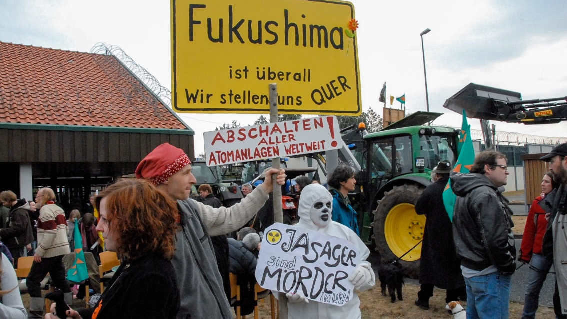 Ein bunte Demo-Szenerie: Unter anderem zu sehen ist ein selbstgebasteltes gelbes Ortsschild, auf dem zu lesen ist: «Fukukshima ist überall.»