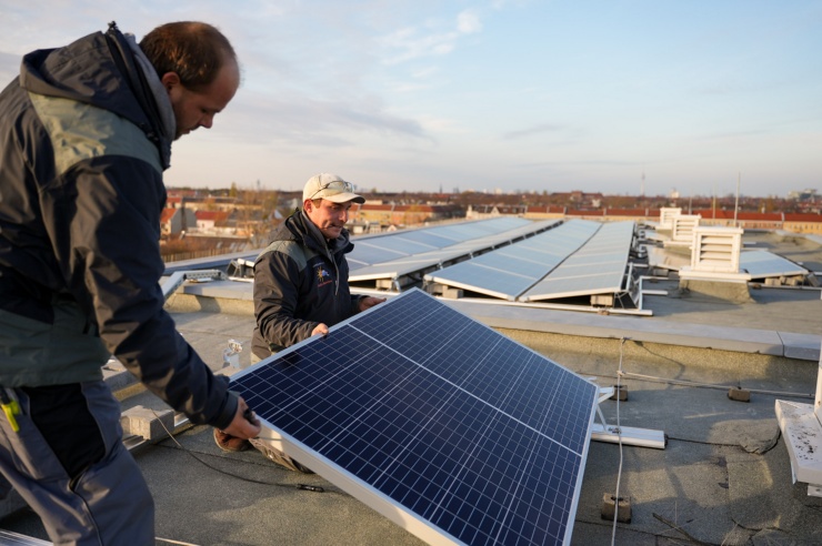 Zwei Solarinstallateure auf einem Dache installieren eine PV Panels.