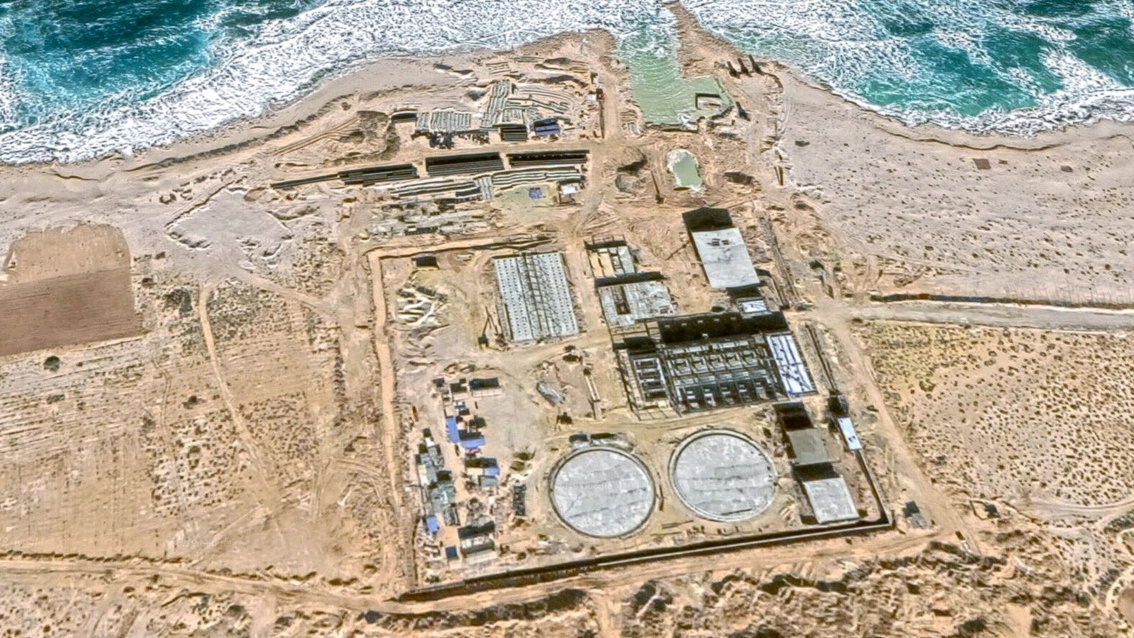 Eine Luftaufnahme zeigt Fundamente für eine große industrielle Anlage auf einen Sandstrand.