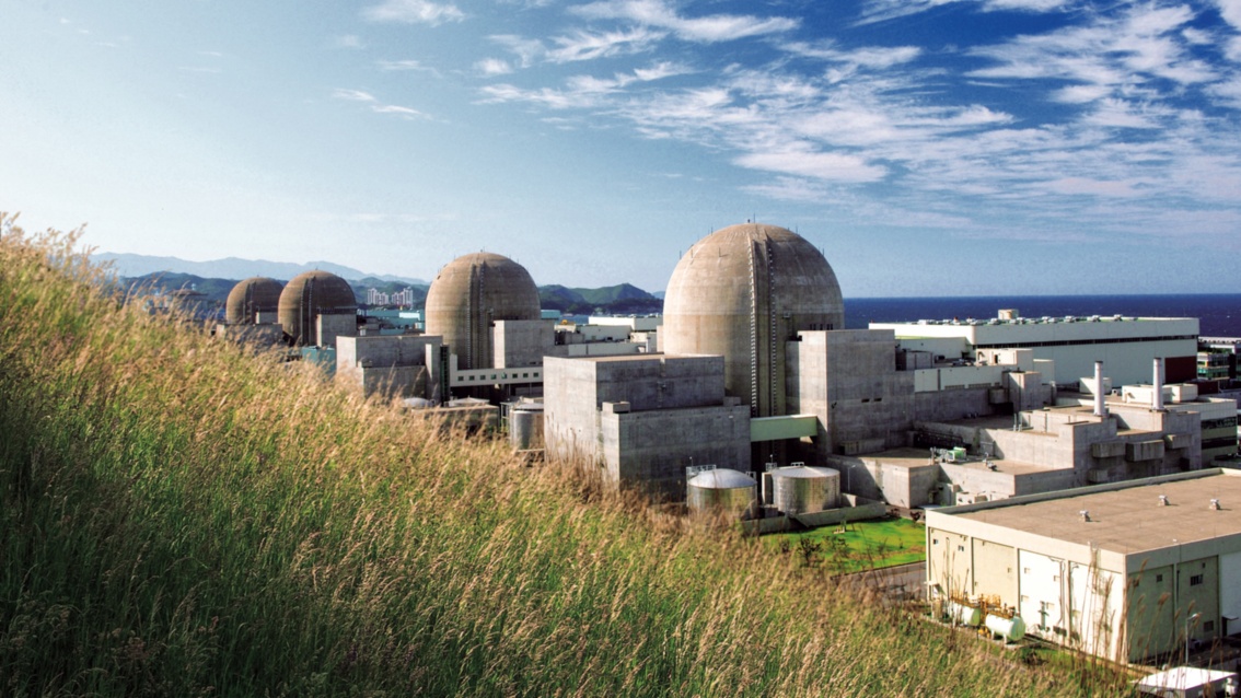 Hinter einer grasbewachsenen Böschung ragen die vier Kuppeln des Reaktors Hanul in Südkorea hervor. 