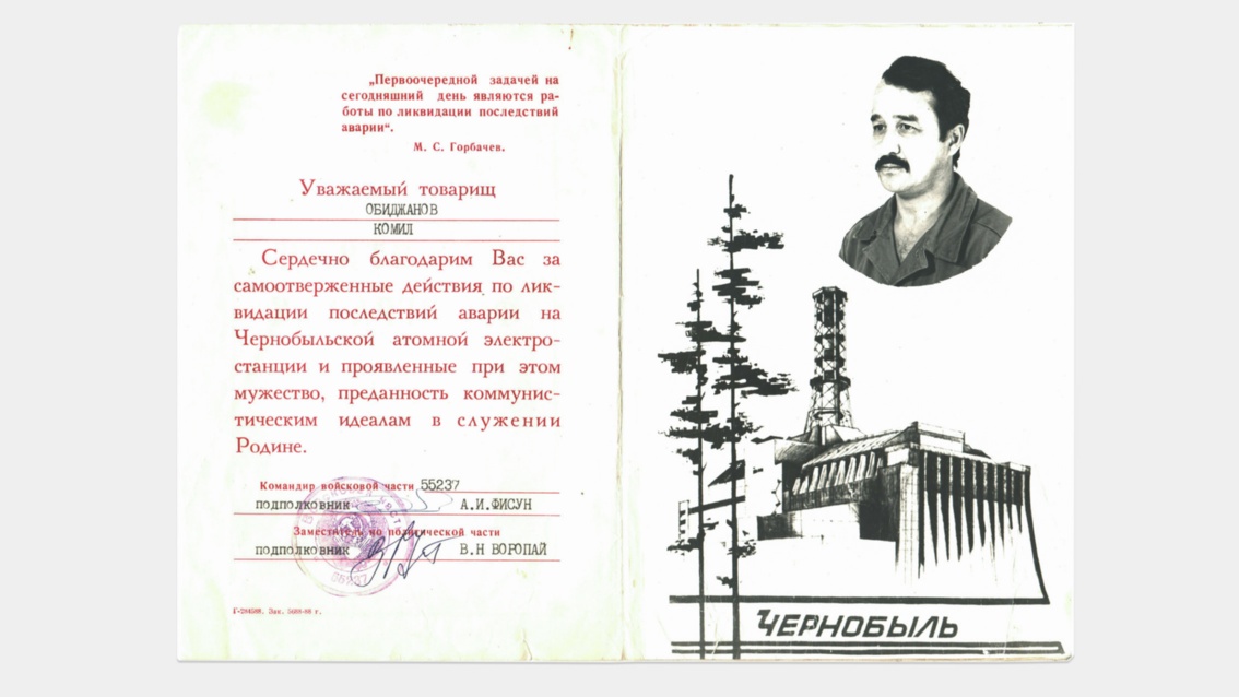 Ein offizielles persönliches Dokument zeigt einen Text, ein Siegel, das Porträt eines Mannes und den stilisierten Umriss des havarierten Atomkraftwerkes Tschernobyl.