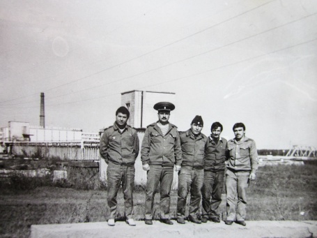 Grupppenbild von Arbeitern, im Hintergrund der Reaktor von Tschernobyl.