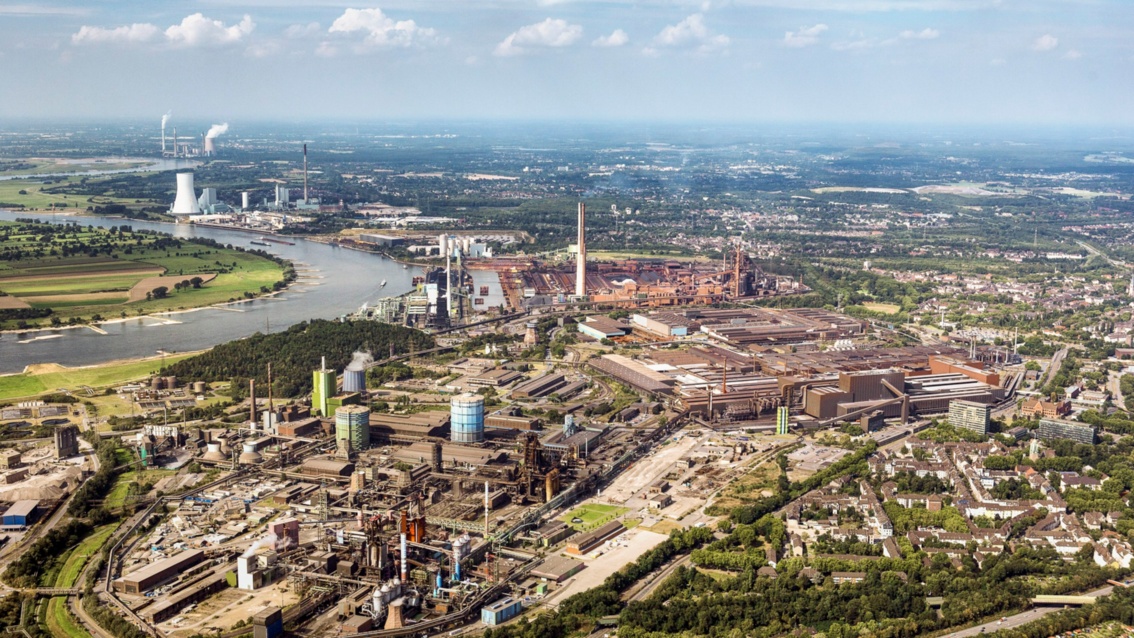 Luftfoto: Blick über ein riesiges Industriegelände, das an einer Flussschleife liegt