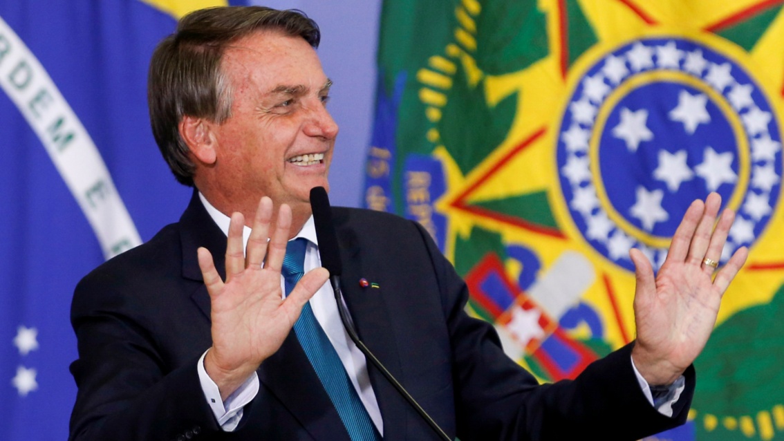 Der brasilianische Präsident, aus der Nähe fotografiert, hebt lachend und abwehrend die Hände.