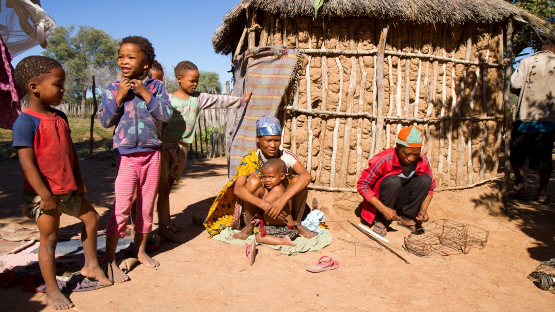 Kinder und Frauen mit schwarzer Hautfarbe in einem afrikanischen Dorf mit Lehmhäusern