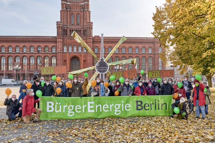 Vor dem Berliner Roten Rathaus sind etwa 40 Menschen zu einem Gruppenbild aufgestellt; hinter ihnen steht ein Papp-Fernsehturm mit goldenen Strahlen.