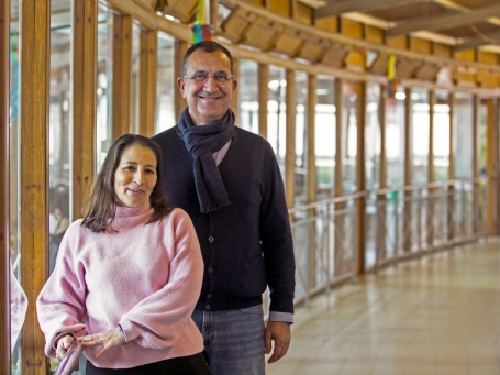 A woman and a man stand in the empty corridor of Centro Júlia Moreira and smile into the camera.