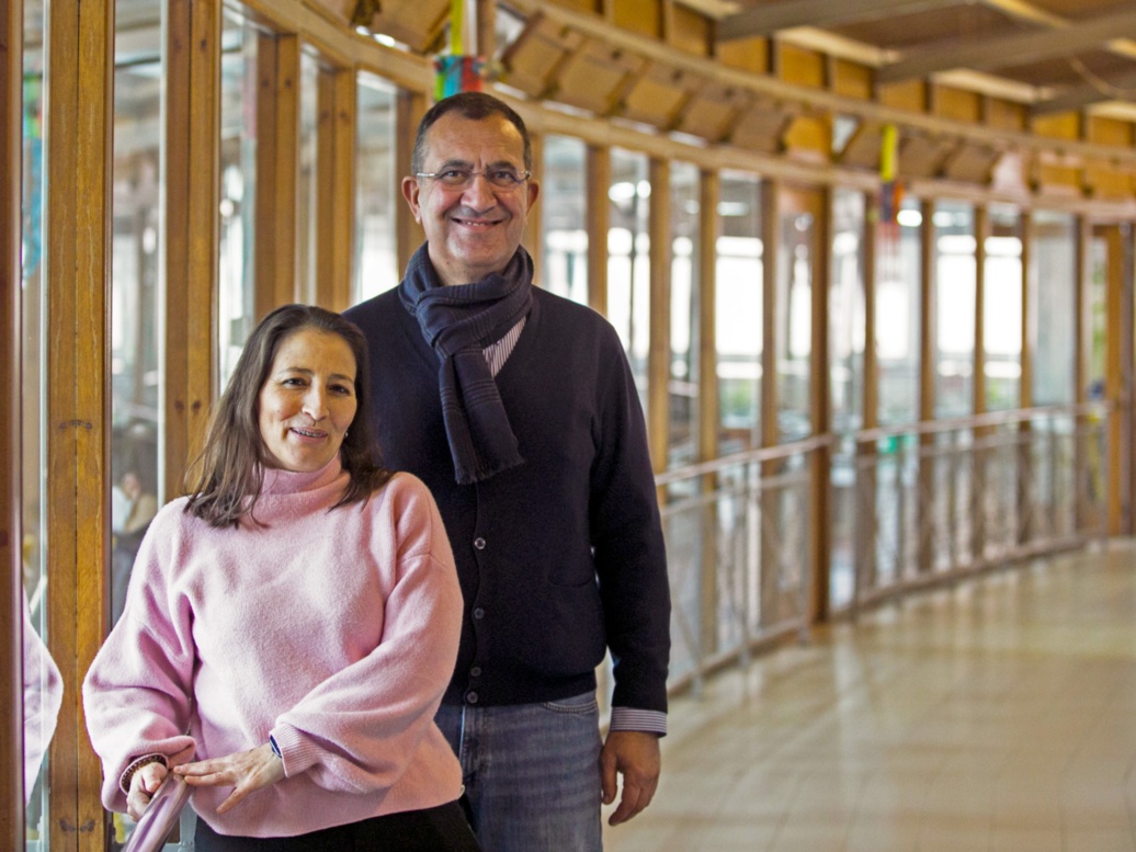 A woman and a man stand in the empty corridor of Centro Júlia Moreira and smile into the camera.