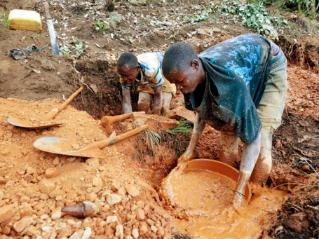 Bergbau mit einfachsten Mitteln: Zwei Männer waschen rote schlammige Erde in Schüsseln.