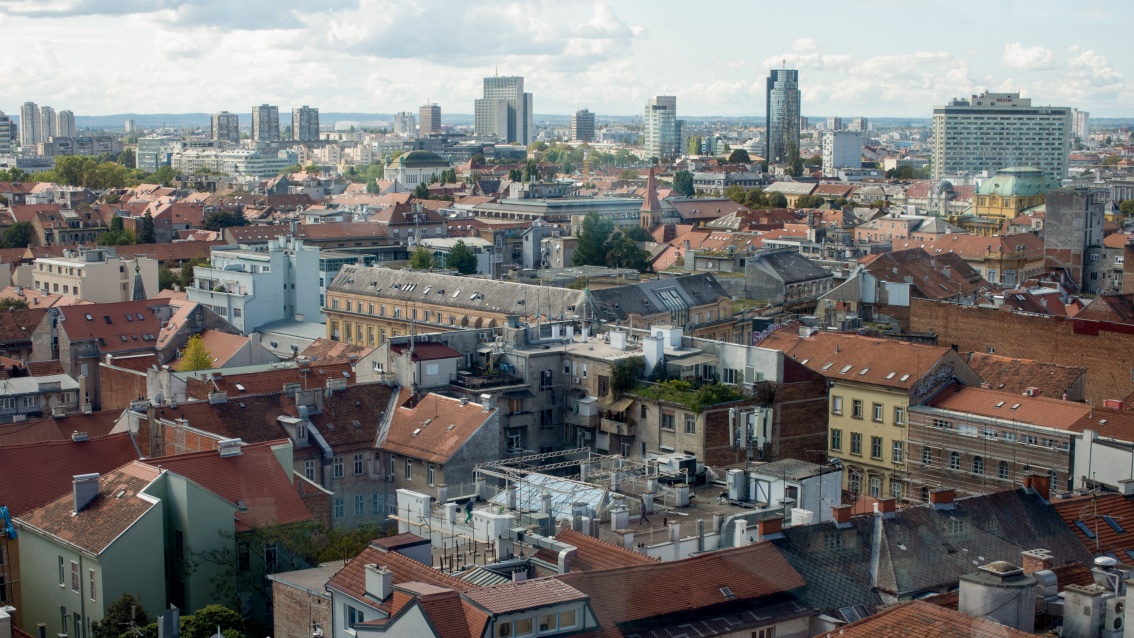 View over the roofs of Zagreb: in the foreground there are many old buildings, further back high-rise residential and office buildings.