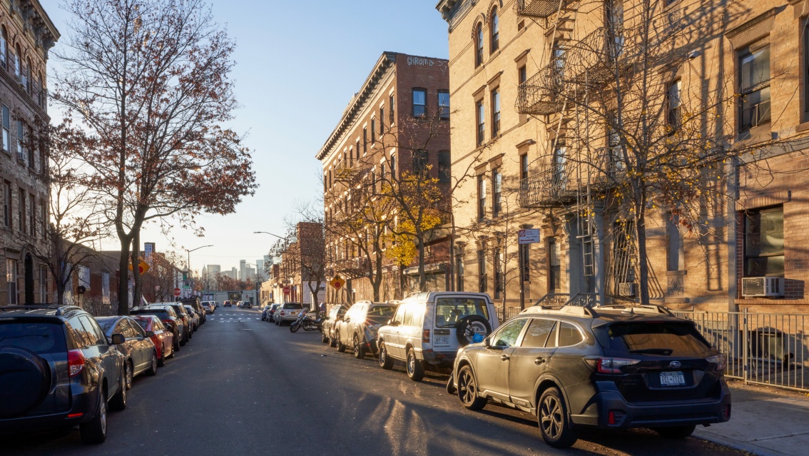 Straßenansicht in Brooklyn: historische Klinkerfassaden werden von warmen Sonnenlicht angestrahlt.
