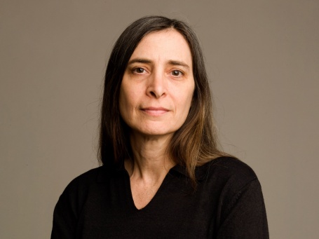 Porträtaufnahme: Eine Frau mittleren Alters mit langem Haar und braunen Augen, trägt einen schwarzen Pullover. 