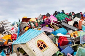 Eine Collage zeigt eine Müllhalde mit vielen Plastikgegenständen, die Szene wirdvon einer darübermontierten schwarzen Rauchsäule verdunkelt.