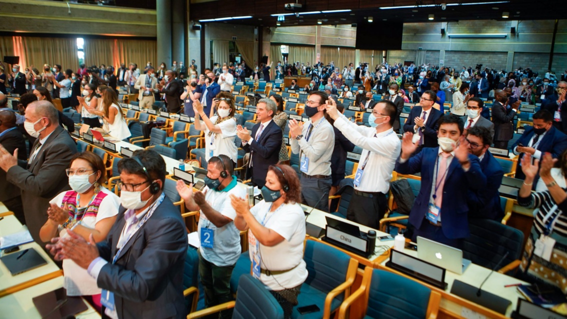 In einem großen Tagungsraum applaudieren unzählige Menschen, mit teilweise zum Jubel erhobenen Händen. 