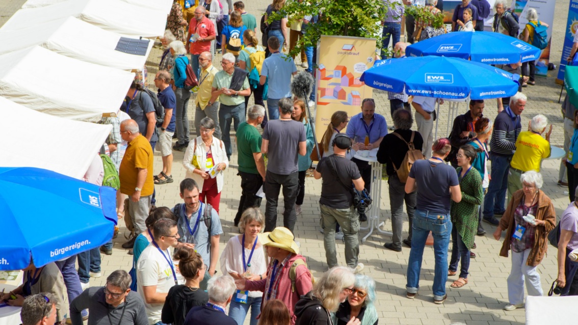 Der Marktplatz von oben: zwischen weißen Zeltständen und blauen Sonnenschirmen tummeln sich zahlreiche Besucher.