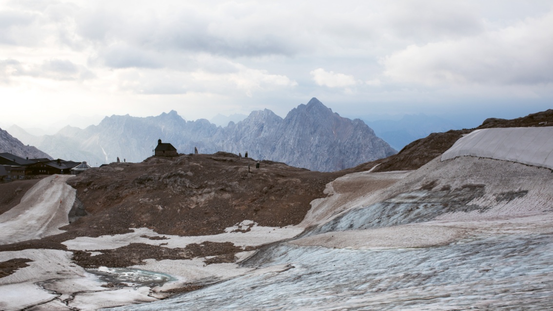 Vor der Kulisse zerklüfteter Alpengipfel steht eine kleine Kapelle – um sie herum befindet sich das Eis auf dem Rückzug. 
